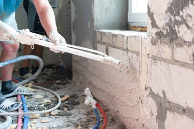 Gastarbeiterlar yeni bir binada mekanize sıva yapıyorlar.