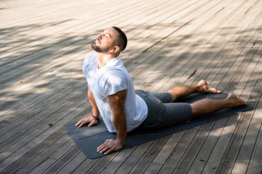 Kobra pozisyonunda yoga yapan yakışıklı yogi adam..