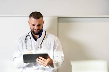 Tablet bilgisayarı olan yakışıklı bir doktorla çevrimiçi tıp. Cihaz ekranına bakıyorlar..