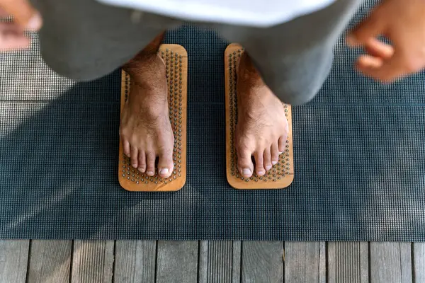 Sadhu board. Man standing on nails. Male bare feet on nails. Yoga practice.