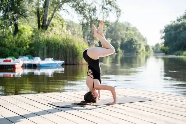 Amuda kalkan kadın sabahları nehir kenarında yoga yapıyor. Sağlıklı yaşam tarzı, uyum ve denge.