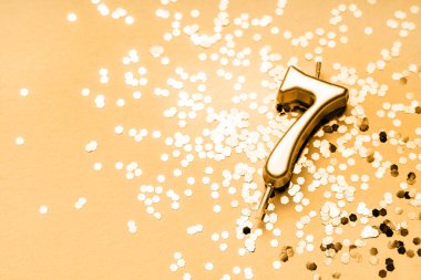 Yedi numara kıvılcımlar üzerinde uzanan altın mumla yapılan 7 yıllık kutlama arkaplanı. Kopya alanı olan evrensel bayram afişi.