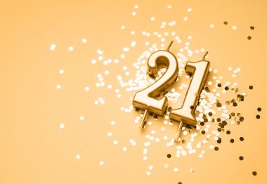 21 yıllık doğum günü kutlaması arka planında 21 numaralı altın mum parıltıların üzerinde yatıyor. Kopya alanı olan evrensel bayram afişi.
