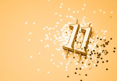 11 yıllık doğum günü kutlaması arka planında altın mumla yapılmış 11 numara pırıltı üzerine uzanmış. Kopya alanı olan evrensel bayram afişi.