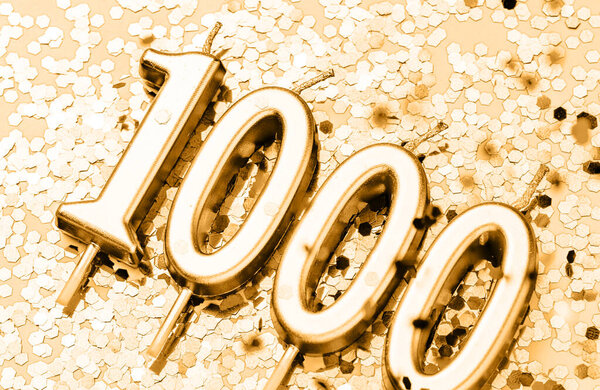 Happy 1000 celebration festive background made with golden candles in the form of number Thousand lying on sparkles. Universal holiday banner with copy space.
