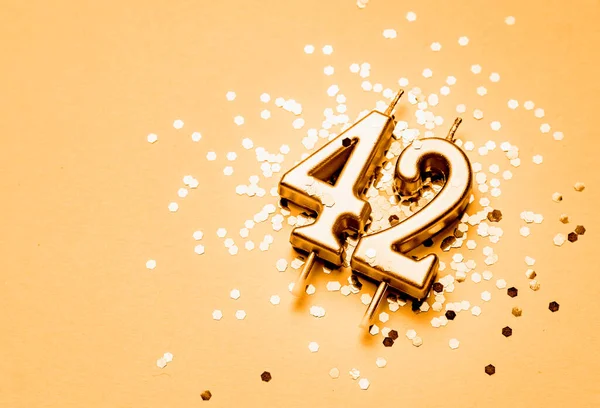 42 years birthday celebration festive background made with golden candle in the form of number Forty two lying on sparkles.