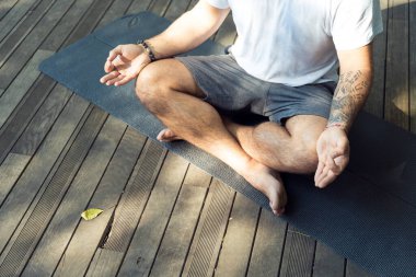 Nilüfer pozisyonunda yoga yapan bir adam doğanın güzelliğinin ortasında huzuru ve farkındalığı yansıtır..