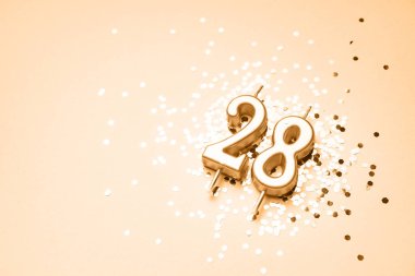 28 years celebration festive background made with golden candle in the form of number Twenty-eight lying on sparkles. Universal holiday banner with copy space. clipart