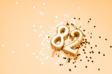 82 years celebration festive background made with golden candles in the form of number Eighty-two lying on sparkles. Universal holiday banner with copy space. clipart