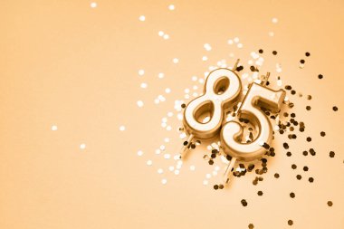 85 yıllık kutlama arkaplanı altın mumlarla süslenmiş 85 numara pırıltı üzerinde yatıyor. Kopya alanı olan evrensel bayram afişi.