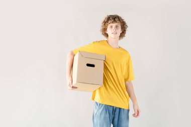 Yakışıklı kıvırcık saçlı genç adam elinde beyaz arka planda fotokopi alanı olan bir kutu tutuyor.
