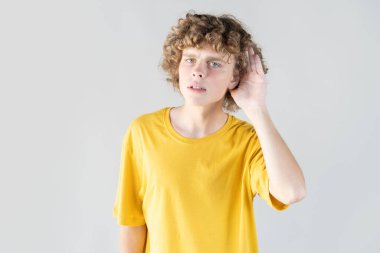 Eli kulağında meraklı genç bir adam, halka açık bir ortamda paylaşılan sırları dinlemeye çalışırken gizlice konuşmaları dinliyor..