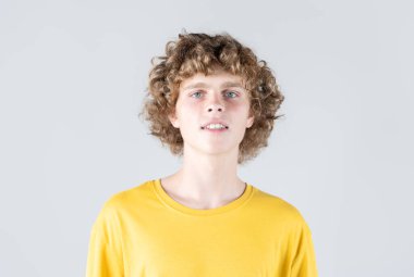 Sarı tişörtlü, kıvırcık saçlı, karizmatik bir adamın portresi. Çekici bakışları kendinden emin bir cazibe ve karizma yayıyor, büyüleyici bir görüntü oluşturuyor..