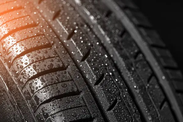Yaz boyunca ıslak yol koşullarında ideal tutuş ve güvenlik için tasarlanmış su damlacıklarıyla birlikte yaz lastiği lastik dokusuna odaklı olarak yakın çekim..