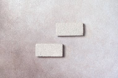 Dekoratif alçı arka planda iki yatay gözenekli taş kaideyle yapılmış düz ürün sunumu sahnesi.