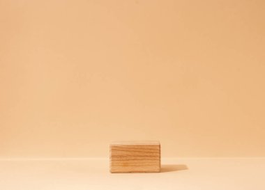 Bej bir arka planda desenli ahşap küp podyumu üzerine kurulmuş güzellik kozmetik ürünleri sergilenen bir model sahne. Bir stüdyo ortamında yakalandı..