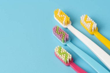 Pembe, sarı, mavi ve beyaz saplı dört renkli diş fırçası, Kopya Boşluğu ile mavi yüzeyde düzenlenmiş..