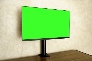 Computer monitor with green screen on wooden desk in modern interior, perfect for mockup design, creative projects and digital workspace visualization.