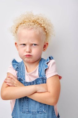 offended girl put hands one by one. cute child is offended and angry. Girl on white background. caucasian curly blonde kid looking at side copy space with with pouty lips. children and human emotions