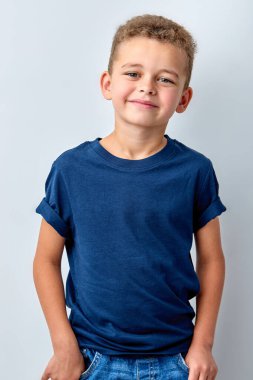 Childhood, youth, human emotions. Optimistic kid boy smiling isolated on white studio background, portrait. little european child posing at camera, friendly and nice, in blue t-shirt.