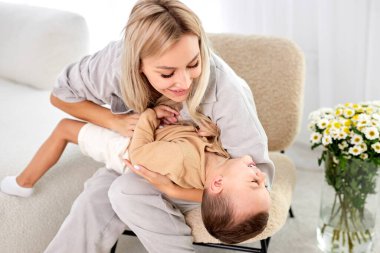 Cheerful mother have fun with son in cozy light living room, laughing, enjoy funny activities on weekend at home,playing together, priceless time of pretty mom with preschool child concept