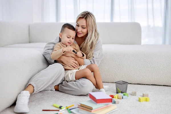 mother has a good time with son of preschool age, laughing. Carefree female parent has fun with kis in living room playing. family mother and kid activity for indoor weekend or quarantine relax