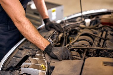 cropped caucasian male mechanic in uniform is working in auto service. Car repair, maintenance and people concept. confident hardworking auto mechanic man at modern clean workshop