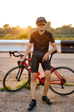Confident Biker man resting during riding the bike in nature countryside. Handsome caucasian Male athlete in cycling gear practising outside. Travel and extreme sport concept.