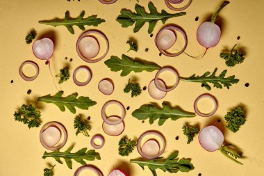 Creative shot of onion slices and fresh herbs isolated on yellow wall background. above view. flat lay, copy space. vegetables with vitamins for healthy lifestyle