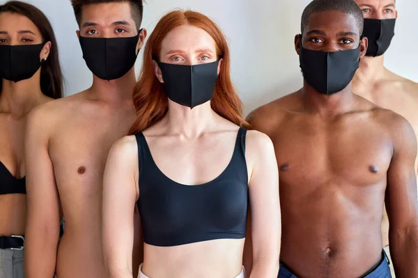 Group of people with protective mask stand looking at you isolated on white background, concept of protection from flu A-H1N1 coronavirus omicron. portrait of diverse people. redhead female in center