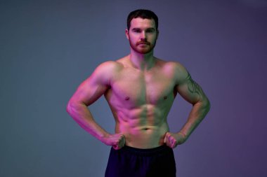 Kolunda dövmesi olan iyi yapılı genç bir adam kameraya poz veriyor. Mükemmel sağlıklı vücut konsepti. izole edilmiş mavi arka plan. diyet