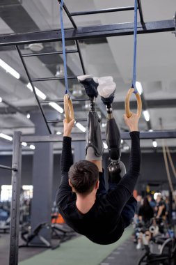 Jimnastik yüzükleriyle inanılmaz bir egzersiz. Hırslı aktif bir adam, jimnastik yüzükleriyle antrenman yaparken vücudunu kaldırıyor. motivasyon.