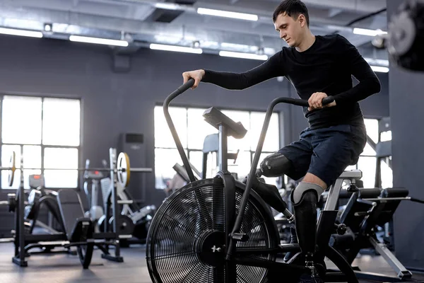 Genç zayıf adam sağlığını geliştirmek için spor salonunda vakit geçiriyor. Yan görüntü fotoğrafı, sağlıklı bir yaşam tarzı, motivasyon.