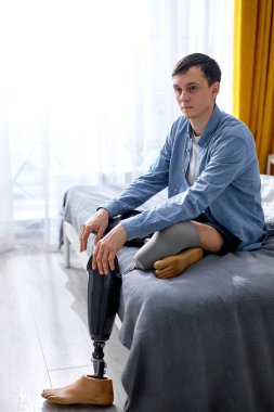 Genç adam bacak ampütesi takıyor ya da evde protez değiştiriyor. Aydınlık bir odada tek başına yatakta oturuyor. Güçlü bir ruhu olan yakışıklı adam asla pes etmez. Sabahları fiziksel engelli bir erkek.