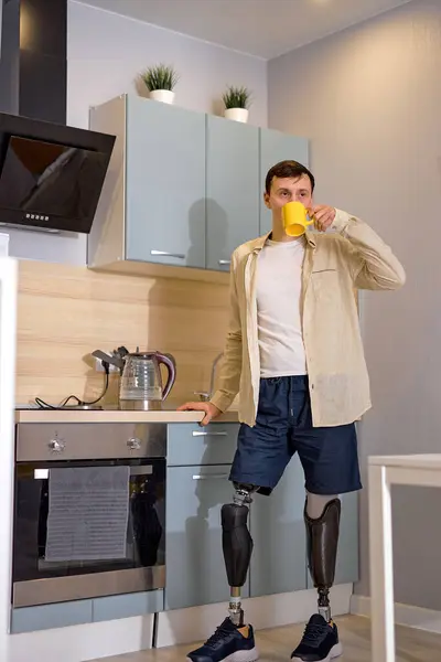 男士们假腿站在厨房里喝咖啡或喝茶 做早操 患有假肢的白人残疾人可以享受早晨或白天的快乐 快乐的残疾人 — 图库照片
