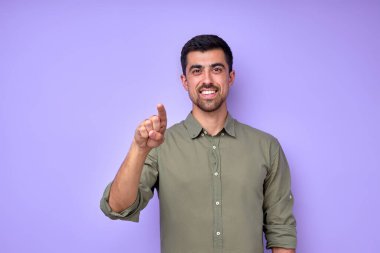 Mutlu gülümseyen, gülümseyen, kamerayı işaret eden, kameraya bakan, mavi arka plan işaretine karşı seni seçen, ön taraftan pozitif ve kendinden emin bir hareket yapan adam.