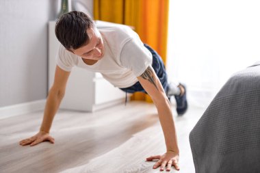 Aktif yakışıklı, beyaz, bacak protezi olan, spor yapan, evde yalnız başına egzersiz yapan, yapay bacaklı bir adam. Engelli sporu ve sağlıklı yaşam tarzı, motivasyon, umut kavramı.