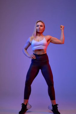 Genç, seksi, kendinden emin, ciddi hırslı bir kadının parmaklarının ucunda durup kaslarını göstermesi. Tam boy fotoğraf. Güç, motivasyon, hobi, halter, ağırlık kaldırma