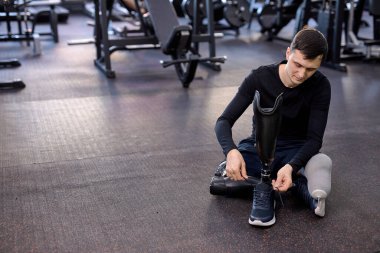 Genç erkek sporcu yapay bacağına spor ayakkabı giyer, engelli adam ayakkabılarını bağlar. Fotoğrafı kapat. Boşluğu kopyala
