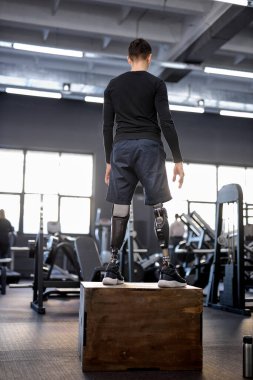 Yapay bacaklı genç adam spor salonunda yere atlayacak. çapraz Sığma