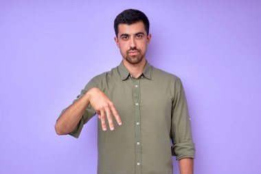 ciddi yakışıklı adam parmaklarıyla M M harfini gösteriyor. Amerikan İşaret Dili ASL alfabesi. izole edilmiş mavi arkaplan yakın plan portresi