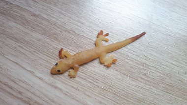 Beyaz duvarda sahte lastik kertenkele oyuncağı. Silikon kauçuktan yapılmış sahte kertenkele..
