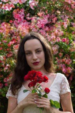 Cildinde gül şekilleri olan romantik görünümlü bir bayan neşeli bir bakışla orada duruyor..