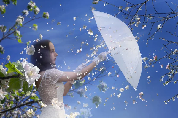 一个快乐的女人拿着雨伞迎接春天的到来 她站在洁白花朵的微风中 — 图库照片