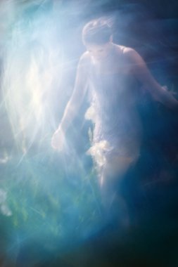 Saf ışıkla aydınlatılmış bir İris çiçeğine, hareketli kristal bir elbise içindeki genç bir kadın yaklaşıyor..