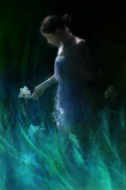 Atmosferik sahne, beyaz bir Iris çiçeğine yaklaşan genç bir kadın..