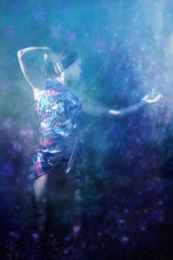 Lale yaprakları giymiş genç bir kadın uzun saçlarını nazikçe okşar. Yumuşak havada düşen bahar çiçeklerini hisseder..