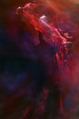 Ritmik alevler, mistik bir atmosferde tutkulu bir kadın dansçının kırmızı peçesinin etrafında uçuşuyor..