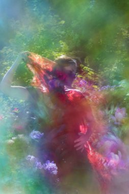 Hafif hareket bulanıklığı içindeki egzotik kadın bahar zamanı katmanlı şakayık dokularıyla dans ediyor..