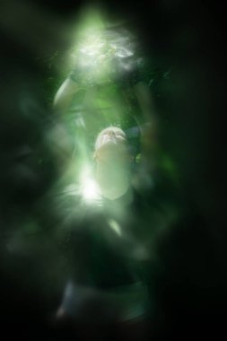 Hafif bulanık poz vermiş, kelebek kanatları gibi hafif şekilli genç bir kadın, benzer bir el hareketiyle gerçekleştiriliyor..